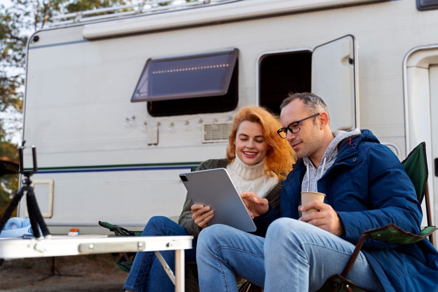seated couple looking at tablet outside of an rv
