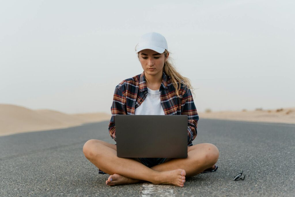 Girl using laptop in the middle of a desert highway