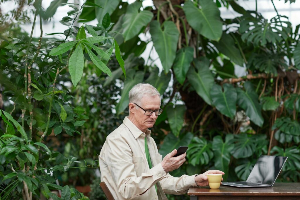 Man trying to use cell phone and laptop at a cafe in the jungle