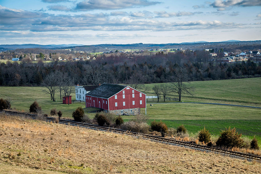 A remote red and grey farmhouse in a field.