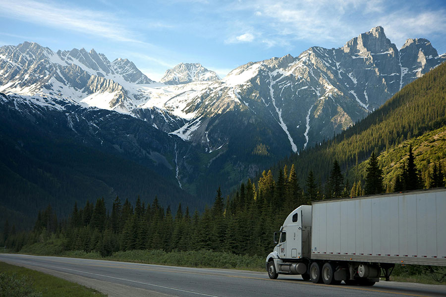 A freight truck drives along a mountain road.
