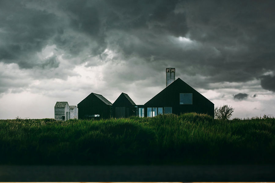 A rural black home under thick clouds.