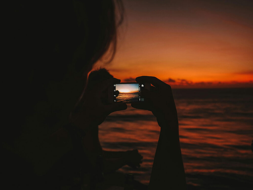 silhouette-of-a-person-taking-a-photo-of-a-sunset-on-a-smartphone